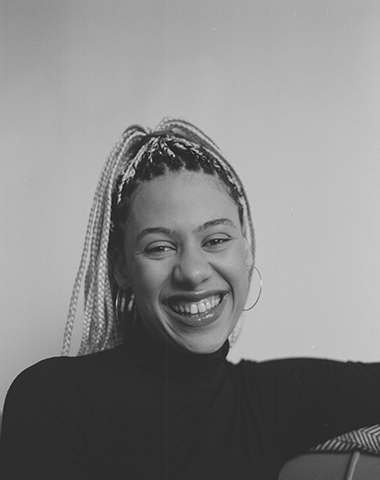 Esme Allman's black and white headshot. The young woman is laughing. 