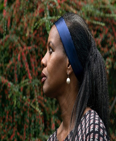Opera singer Ruby Philogene shot in profile with a blue hairband and a pearl earring. 