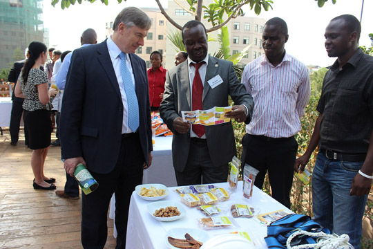 Stephen Isiko, a local business man, showing the Secretary General, David Cooney, what his company produces